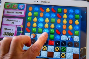 A person plays on his tablet with Candy Crush Saga games developed by British King Digital Entertainment, on March 6, 2014, in Lille, northern France. The game is free, but players can pay for in-app extras to help them pass up through its more than 500 levels. Millions of commuters, teenagers -- even pensioners -- clock in daily to test their skills at the game, which involves lining up tiny pieces of colored sweets to make them vanish from the screen of their computer or mobile phone. AFP PHOTO PHILIPPE HUGUEN (Photo credit should read PHILIPPE HUGUEN/AFP/Getty Images)